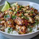 Colorful Thai Peanut Chicken Bowl garnished with fresh cilantro, chopped peanuts, and lime wedges on the side.