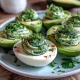 Green avocado deviled eggs with creamy filling and fresh herbs, perfect for spring parties.  