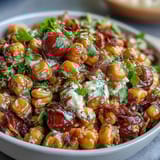 A bowl of creamy corn salad with jalapeño, featuring juicy tomatoes, cilantro, and a smoky lime dressing for bold flavor.  