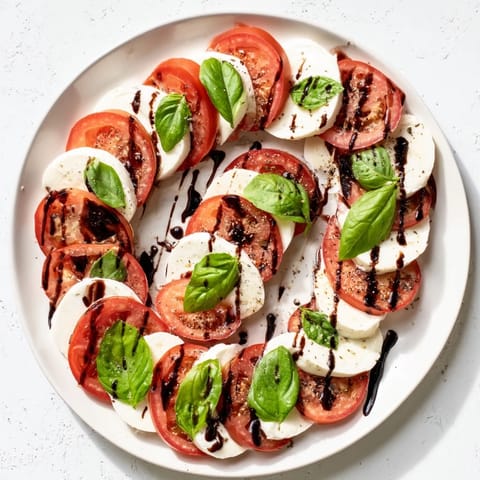 Vibrant Caprese Salad on a white plate with olive oil and sea salt, ready to serve.