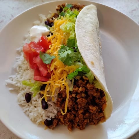 Golden-brown grilled Beef Burrito sliced in half, revealing layers of savory beef, rice, beans, and fresh lettuce.