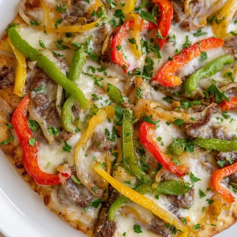 Slice of Philly Cheesesteak Pizza featuring juicy ribeye steak and bubbling three-cheese blend.