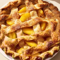 Freshly baked Peach Pie with a golden flaky crust and bubbling peach filling, served warm with a scoop of vanilla ice cream.