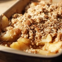 Freshly baked Apple Crumble with bubbling cinnamon apples under a golden, crunchy topping, served warm in a rustic dish. 
